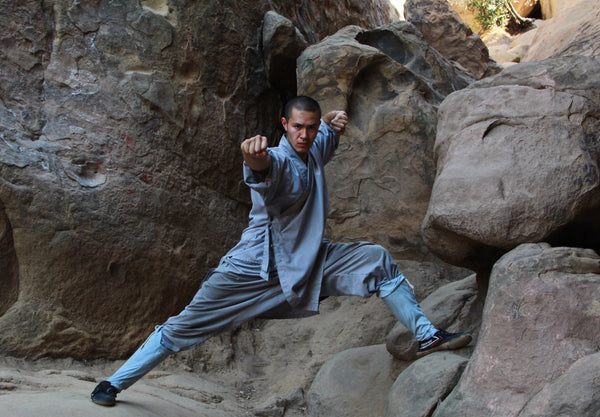 A Shaolin disciple holding a Kung Fu posture on rocks below Songshan
